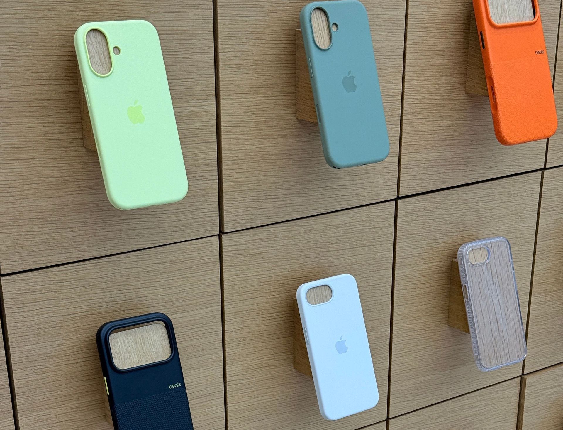 A variety of colorful phone cases displayed on a sleek wooden wall in a store.